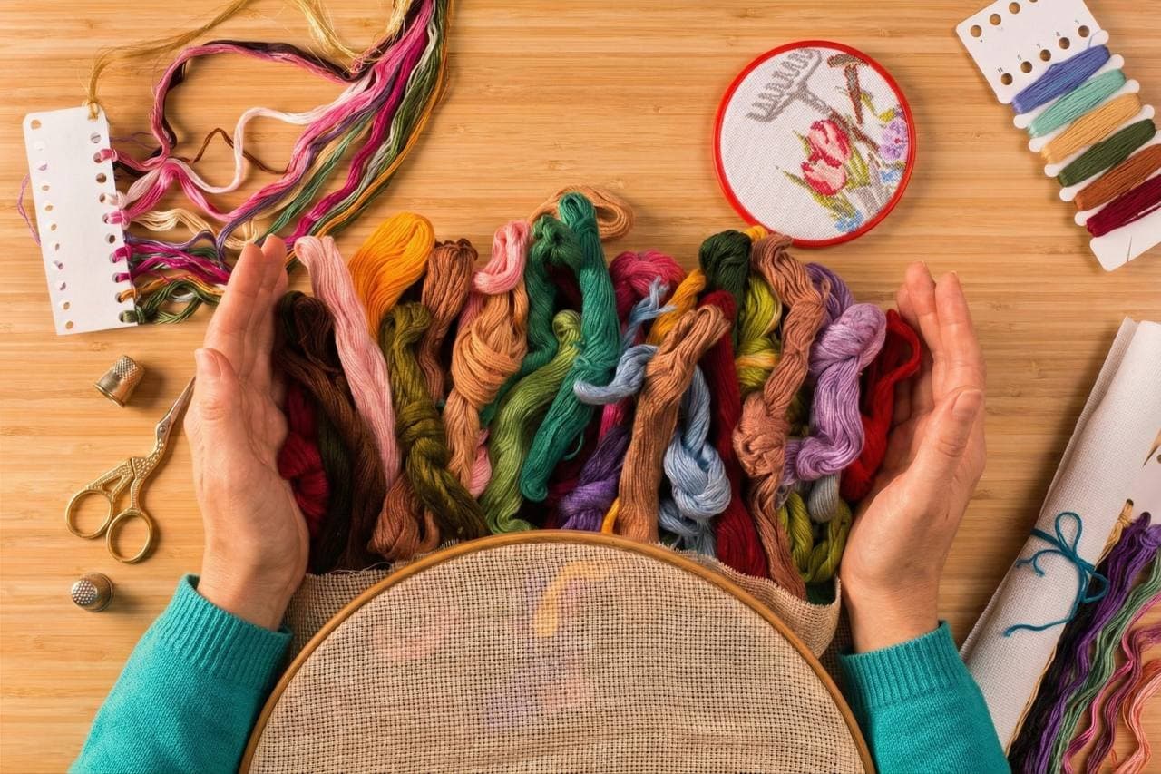 DMC embroidery floss skeins, hoop, thimbles and scissors — a stitcher's full toolkit
